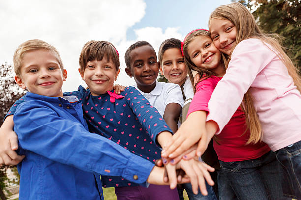Multiracial school children putting their hands together
