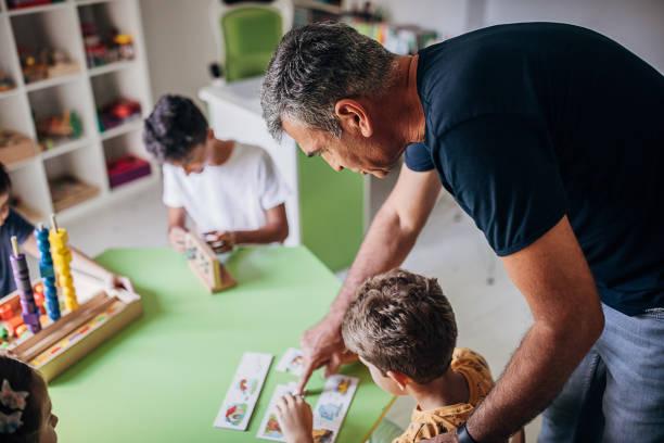 Group of people, kids with adult male therapist learning motor skills and color differences together.